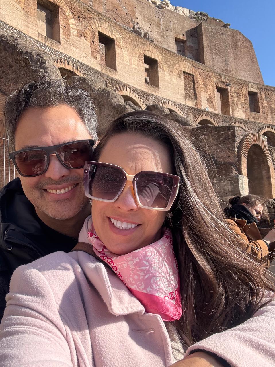 Selfie do casal diante dos arcos do Coliseu